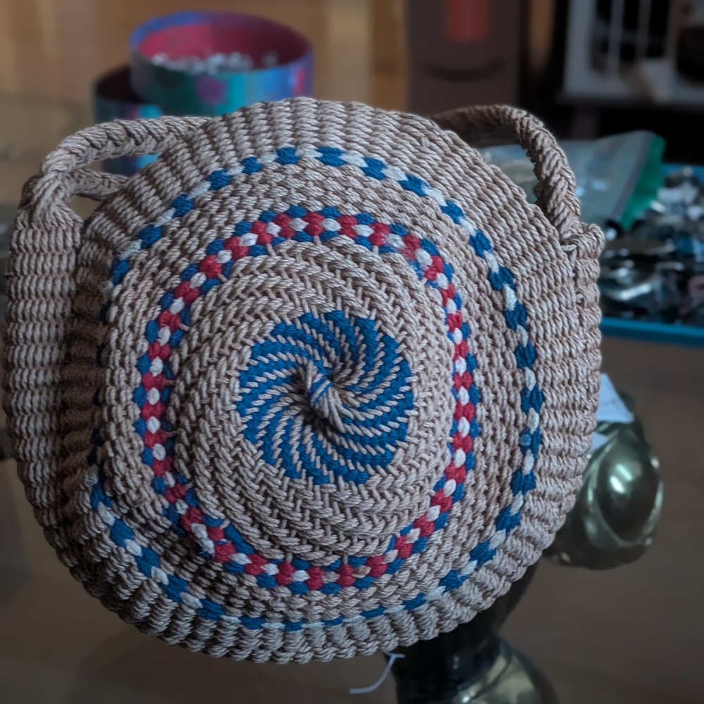 handmade round woven rattan bag with a red, white, and blue spiral pattern.